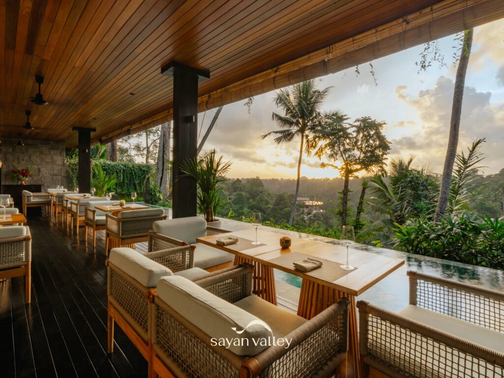 Sunset open-air dining overlooking the jungle valley at Sayan Valley Ubud, luxury resort restaurant with elegant seating and panoramic tropical views in Bali.