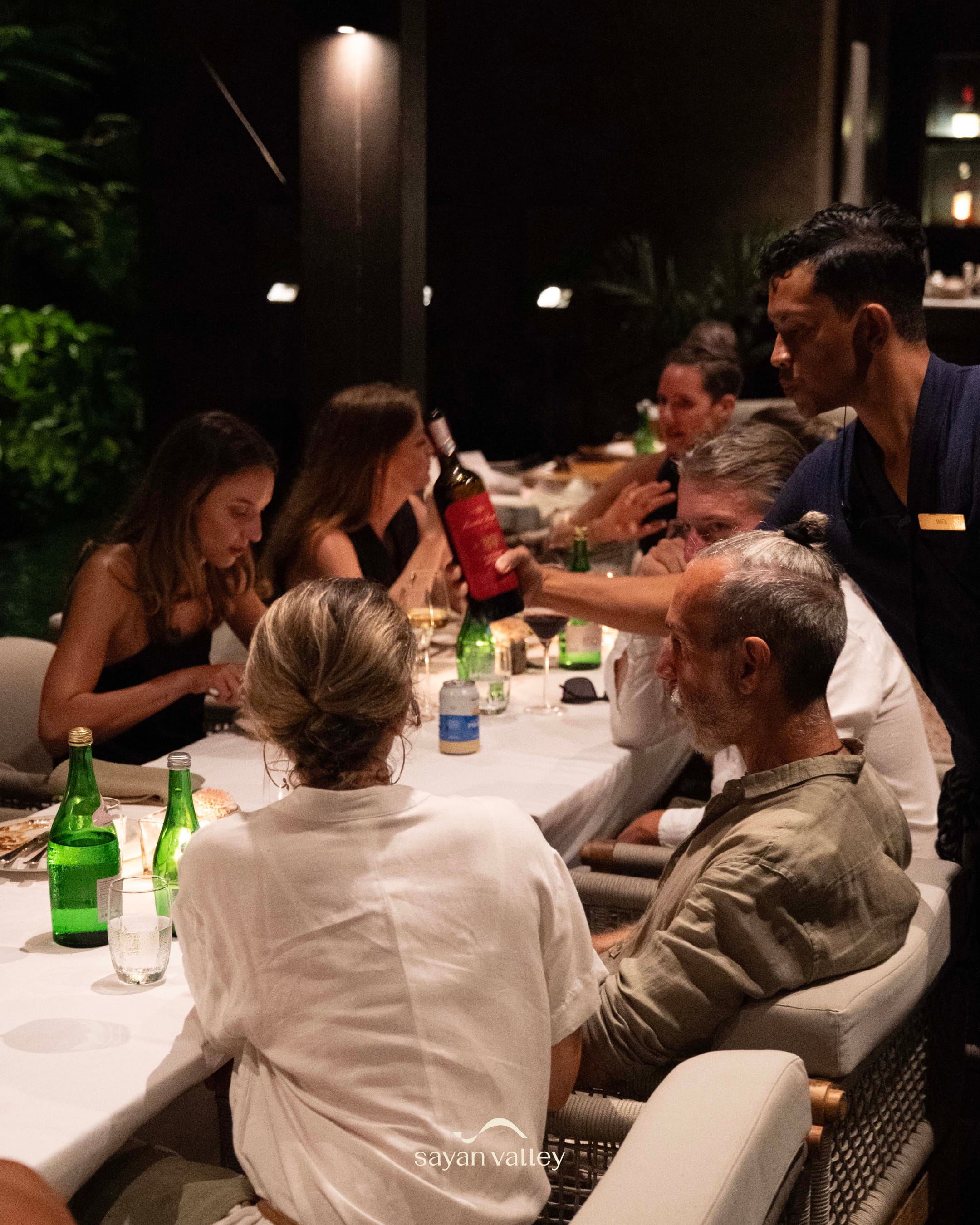 Friends enjoying a wine dinner at a luxury restaurant during the peak sunset time in bali