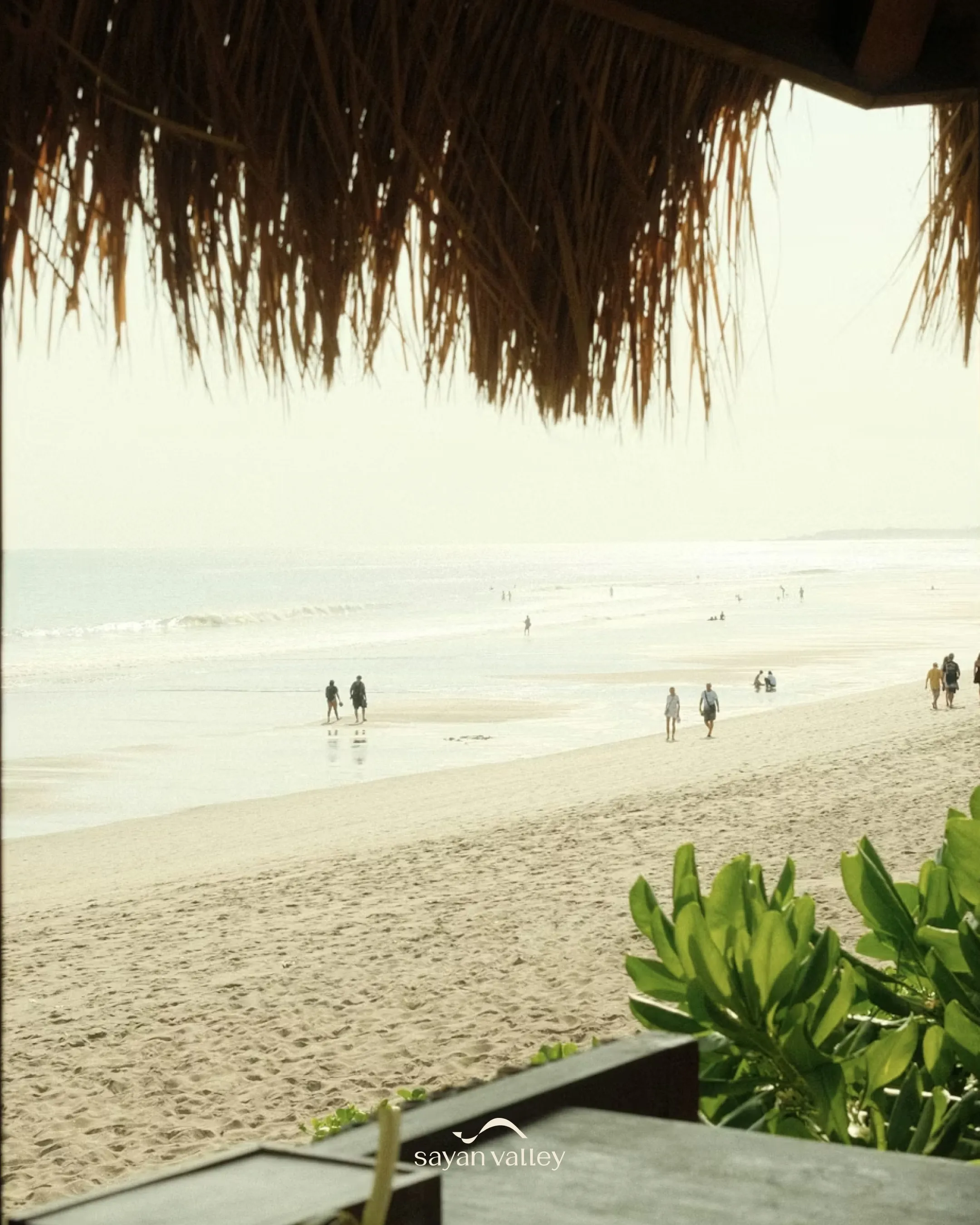 seminyak-beach-bali-relaxing-sunset-spot Silhouetted guests relaxing under thatched umbrellas during the golden sunset in bali time.
