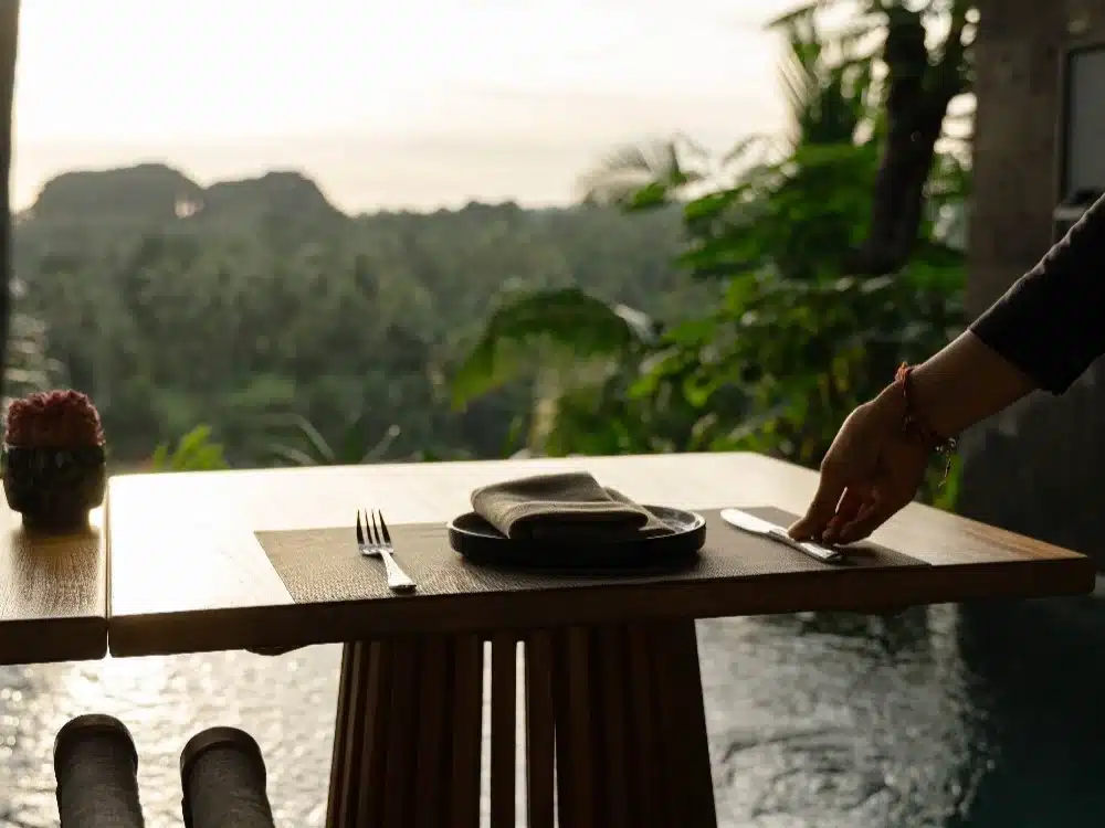 Silhouette of a waiter serving drinks at a beach club during the peak bali sunset time.